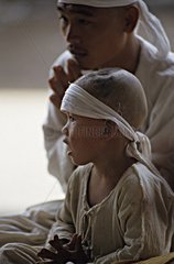 Kind und Mann  die die Beerdigung Kambodscha feiern