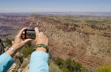 Womans hands taking photograph fron the South Rim of the famous Grand Canyon fron above in Arizona USA