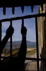 Looking out thru rusted gate with arms reaching to outside of the famous landmark Alcatraz Prison on bay island in San Francisco California