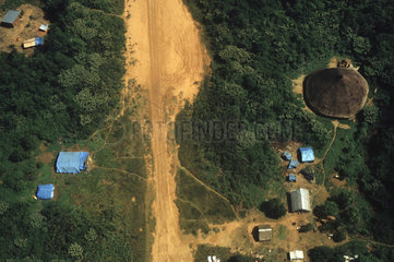 Illegal landing-strip at Yanomami indigenous people territory. Paapiu ( or Papiu ) area  Roraima State  Amazon rain forest  Brazil. Gold miners invasion of native land. Acculturated indians  indigenous house and gold mining tents.