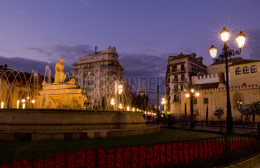 Beautiful night time exposure of fountain and flowers at Puerta de Jerez square with excitement in Seville Spain downtown