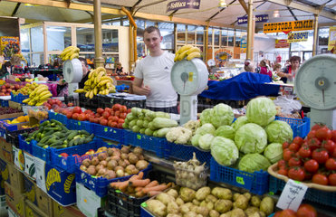Man selling fruit and vegetabkes in indoor market in city center of Lviv Ukraine
