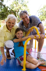Grandparents with granddaughter family having fun outdoors in park on colorful ride with love and caring