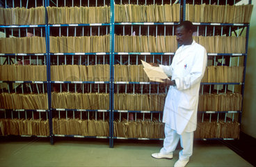 A doctor is reading documents from the hospitals archive. This one is still analogue and computers are in demand on district level. Chimoio provincial Hospital. Manica. Mozambique
