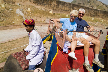 Retired tourists on holiday having colorful elephant rides at Amber Fort in Rajasthan Jaipur India