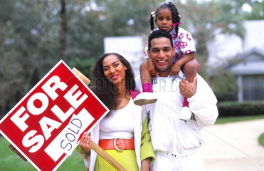 Black african american family outside having bought a new home with the sale sign with caring and love
