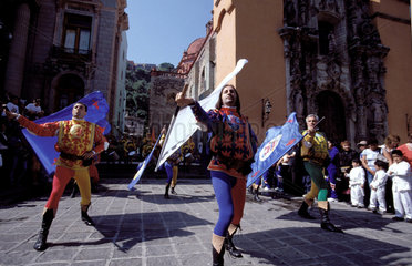 Mexico  Guanajuato; costumed men with flags in a historical parade  with audience and drumband at the background