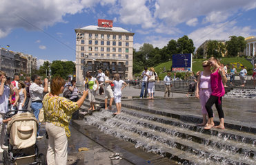 People playing in street fountain and taking photo near Independece Square in city center of Kiev Ukraine