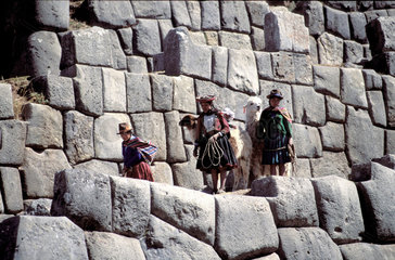 Peru  Cusco region; Native people in traditional clothing with lamas are walking on the huge stones that form the remains of the well known inca wall complex sacsayhuaman.
