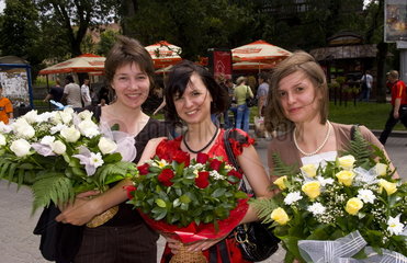Young women having fun carrying flowers in downtown city center of Lviv Ukraine