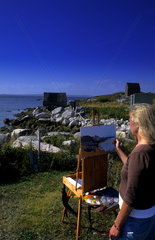Woman artist painting scenic in Peggys Cove area in Nova Scotia Canada