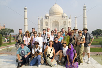 Tourist photograph club group photo in front of the peaceful Taj Mahal one of the wonders of the world in Agra India