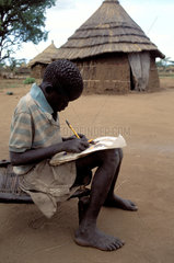 Sudan. Refugee boy doing his homework.