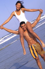 Attractive black african american couple in swim suits relaxing on the beach on holiday and enjoying the togetherness and caring