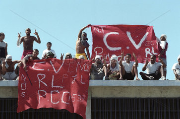 Rebellion in reformatory prison  Rio de Janeiro  Brazil. Penitentiary revolt  mutiny  insurrection. Prisoners from criminal faction Comando Vermelho or CV ( Red Command ) hold the faction flag on the penitenciary roof. Violence  delinquents  outlaws.