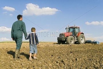 Bauer mit seinem Sohn in einem gepflügten Feld Frankreich