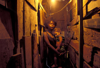 Poor family lives in an abandoned school in a Rio de Janeiro shantytown  Brazil. Slum  Black girl holds child  tenderness  poverty  homeless family in Latin America  homelessness.