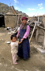 Native poor farm woman with her grandchild at poor home in rural country outside the city of Lhasa Tibet China