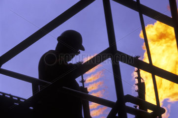 Labor  worker at petroleum industry wearing safety gear ( helmet  glasses ). Fire  insalubrious  unhealthy job  employment. Brazil.