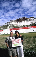 ourists with homemade sign in front of the wonderful Potala Palace on mountain the home of the Dalai Lama in capital city of Lhasa Tibet China