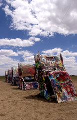 Tourist taking picture with camera at the Cadillac Ranch with buried cars in ground in Amarillo Texas USA