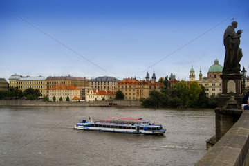 River boat on Vitava River and the famous Charles Bridge of tourist city of Prague in Czech Republic
