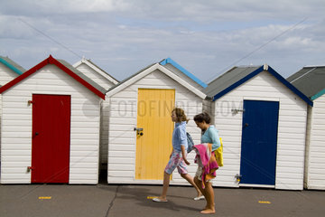 Girls walking by colorful bath houses in Paignton in England Devon called the English Rivera