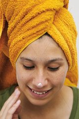 Woman applying cream on her face skin after bath
