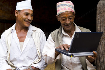 Great image of modern technology with local Hindu men and new laptop computer in village of Bhaktapur a town near Kathmandu Nepal