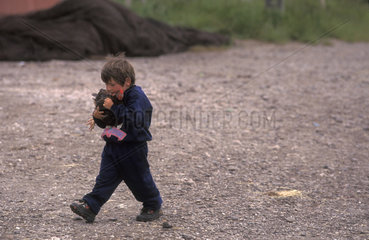 8-years-old boy wearing coat  holding chicken and walking at Chiloe island  Chile. South America  Latin America  child  children  daily life  coolness  cold  coldness