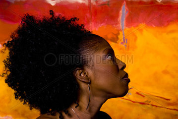 Profile portrait of Cameroon Africa woman with wild hair in front of colorful artwork