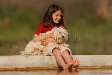 Mädchen mit einer Tulear -Baumwolle am Rand eines Pools