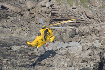 Helicopter air sea rescue above rocks at Widemouth Bay UK