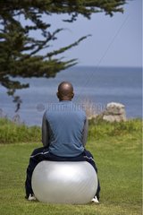 Man sitting on a ball facing the sea Monterey California