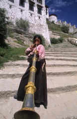 Young girl playing musical horn at the wonderful Potala Palace the home of the Dalai Lama in capital city of Lhasa Tibet China