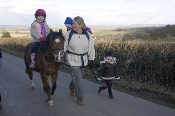 Mother and three children out walking with pony Cotswolds UK