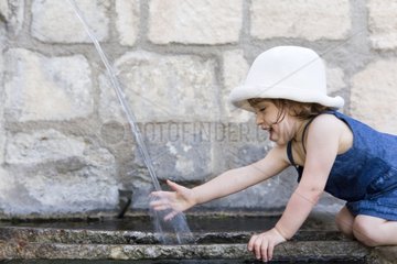 Girl playing with water from a fountain Gordes Provence