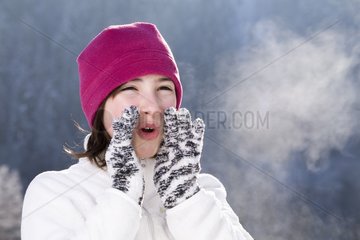 Small girl blowing hot air in the mountains