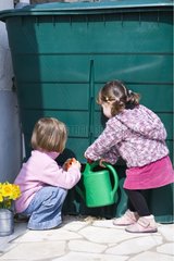 Two small 3 and 4-year-old girls fill a sprinkling can