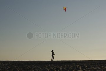 Jeune femme jouant au cerf-volant sur la plage France