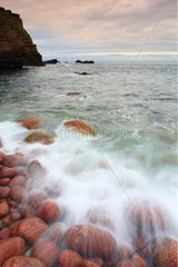 Waves breaking on red sandstone peebles Scotland