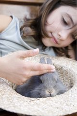 Girl playing with his dwarf rabbit in a hat France