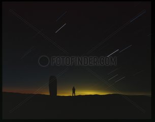Sunrise on a Mount Lozère menhir and a man Cévennes France