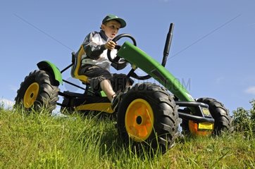 Boy driving a kart pedal in a meadow France