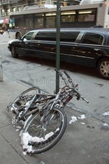 Bike attached to a pole and limousine in New York