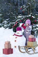 Small girl and presents on a sledge with snowman