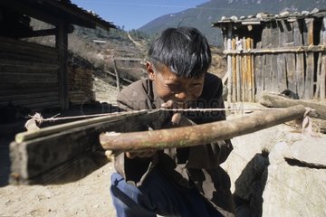 Yi child playing with his crossbow Yunnan China