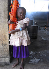Portrait of a young girl carrying a stack of feeding cups at an MSF feeding centre in Angola. Feeding centres and other humanitarian aid were organised in Angola after widescale malnutrition during and following the countrys civil war.