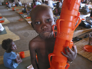 A boy carries a stack of feeding cups at an MSF feeding centre in Angola. Feeding centres and other humanitarian aid were organised in Angola after widescale malnutrition during and following the countrys civil war.
