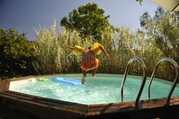 Child jumping in the pool in summer France